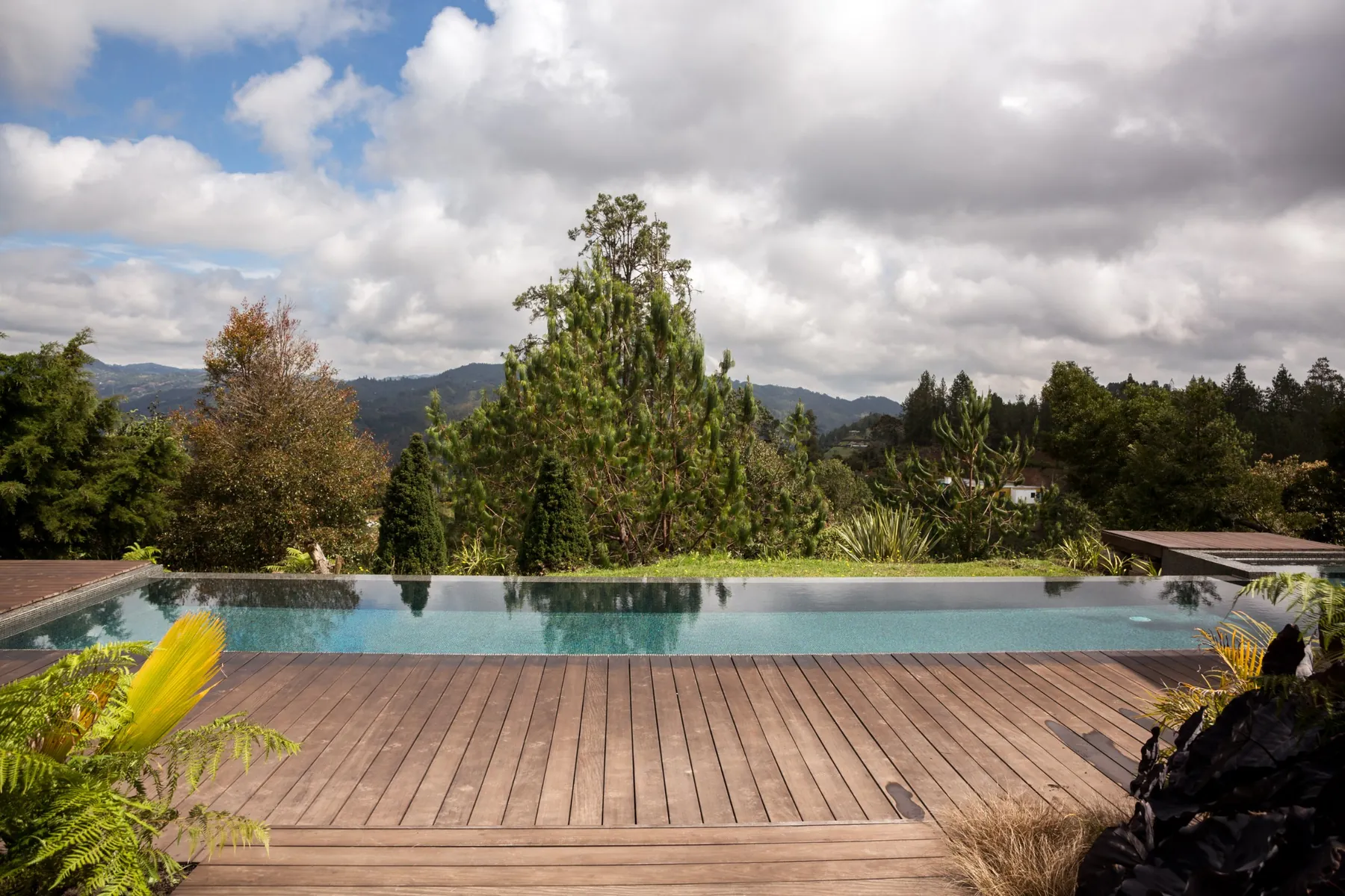 Deck en madera junto a la piscina infinita, Casa 64